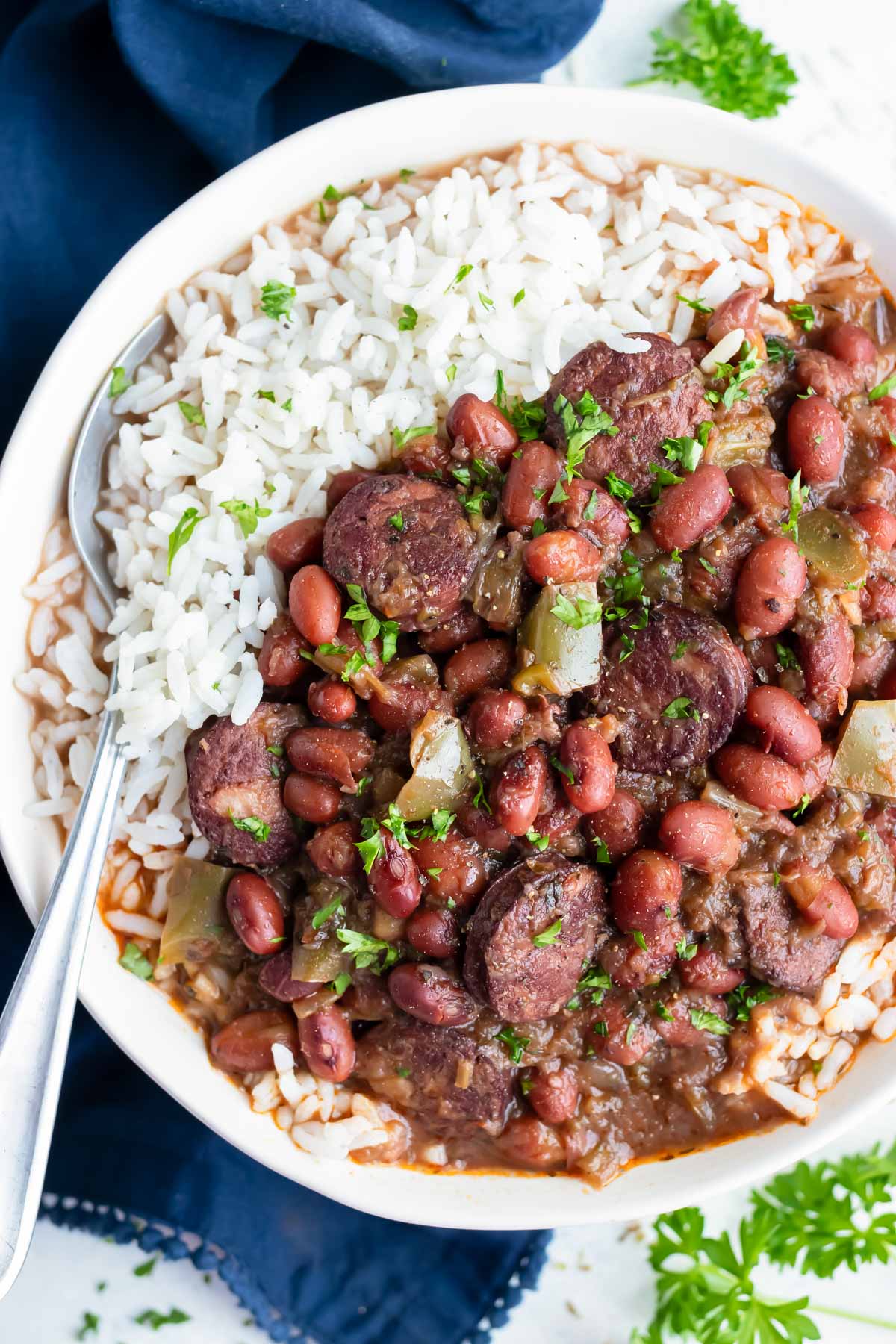 Instant pot red beans and rice are eaten with a spoon from a white bowl.