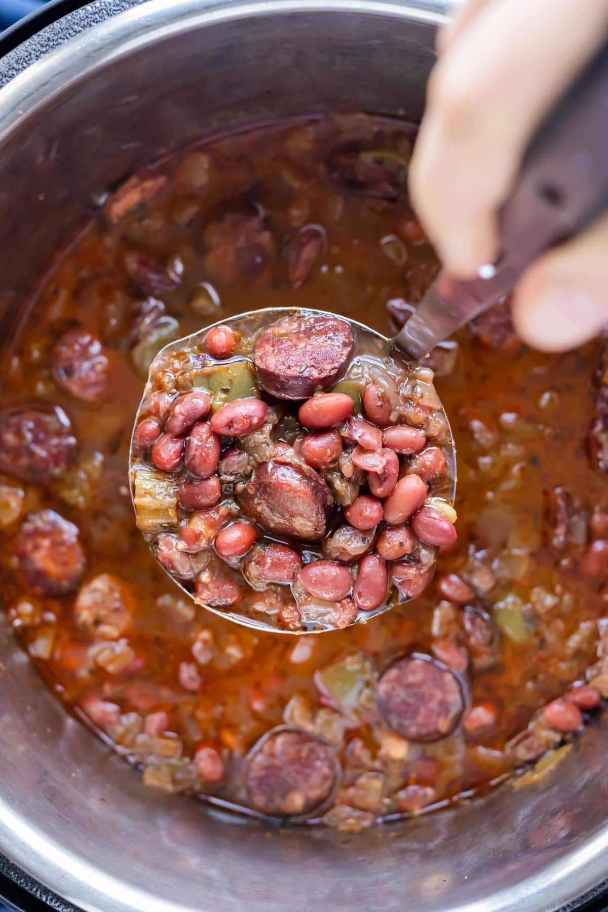 A ladle lifts up a serving of red beans and rice.