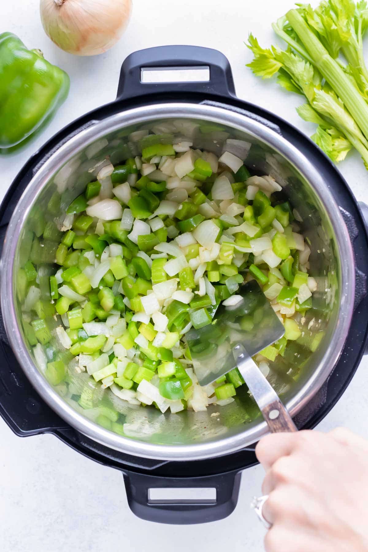 Bell peppers, onions, and celery are sautéed in the instant pot.