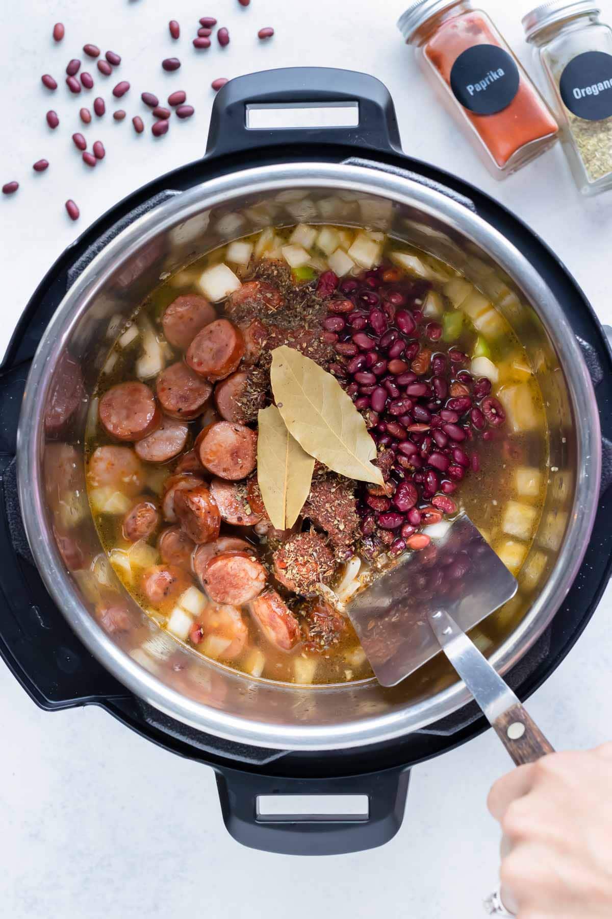 Red beans, bay leaves, and sausage are added to the instant pot.
