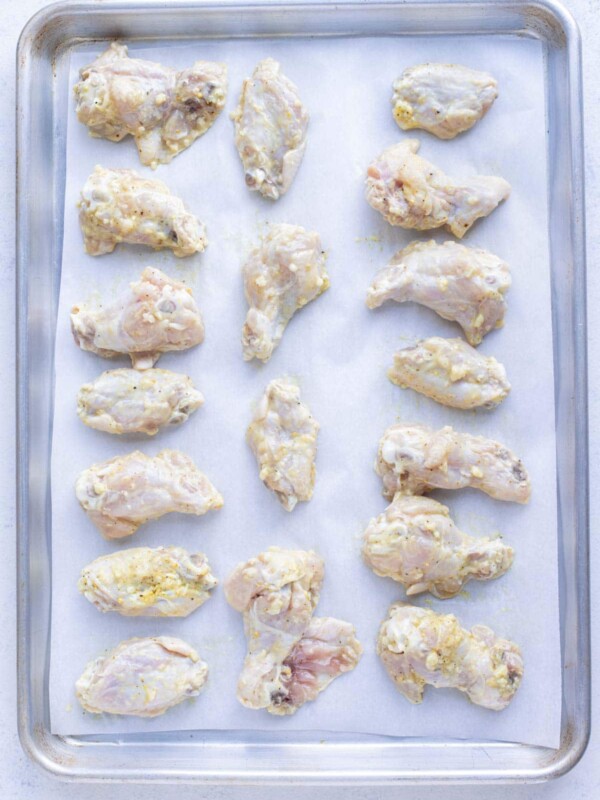A layer of chicken wings are prepped to cook in the oven.
