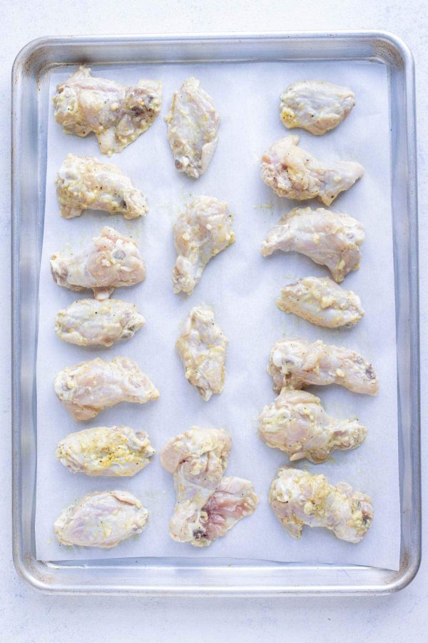 A layer of chicken wings are prepped to cook in the oven.