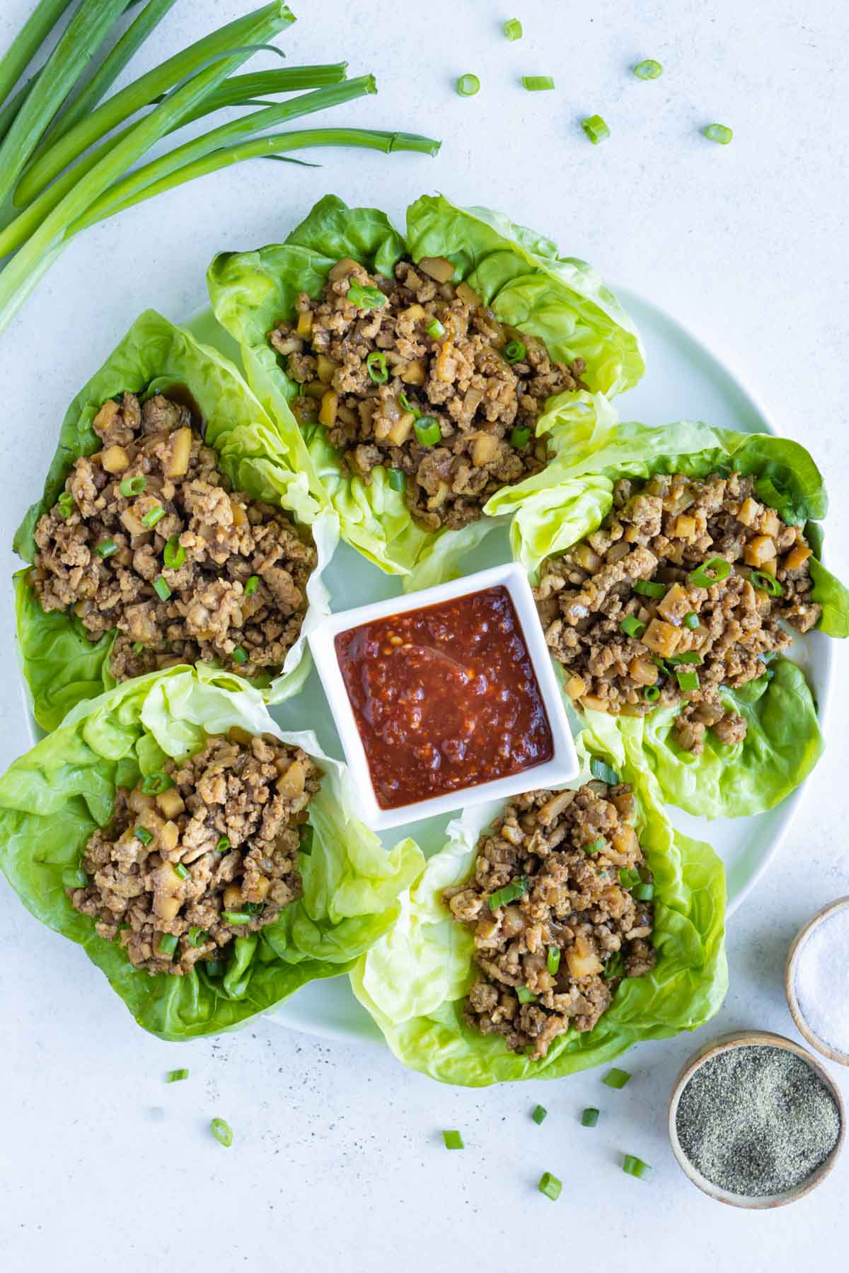 A plate of copycat Asian Chicken Lettuce Wraps are shown from overhead.
