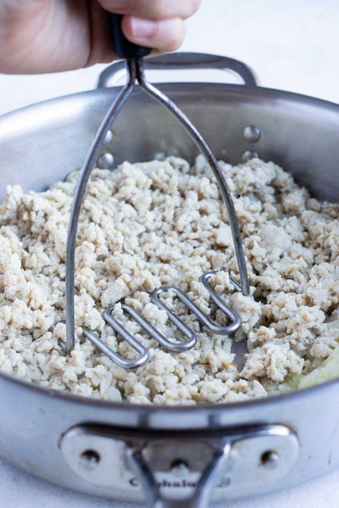 Ground chicken is cooked in a skillet.