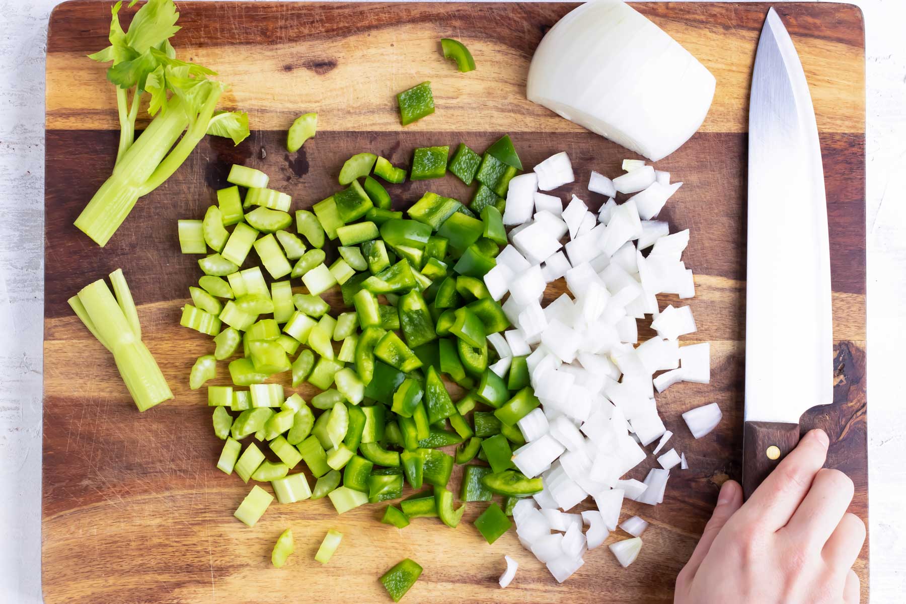 A cutting board shows diced celery, bell pepper, and onion.