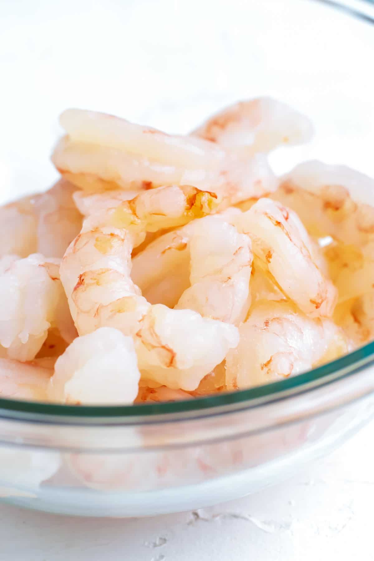 A clear bowl full of fresh, wild, 20/24 count shrimp.