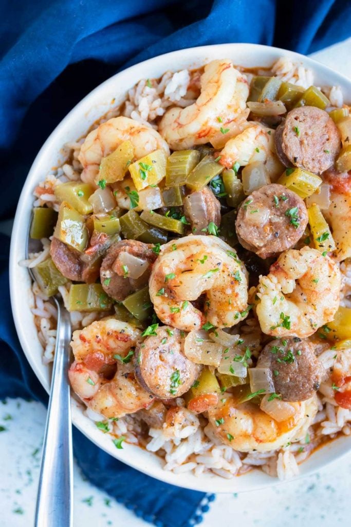 Loaded shrimp and sausage gumbo, made with a homemade roux, is eaten from a bowl with a spoon.
