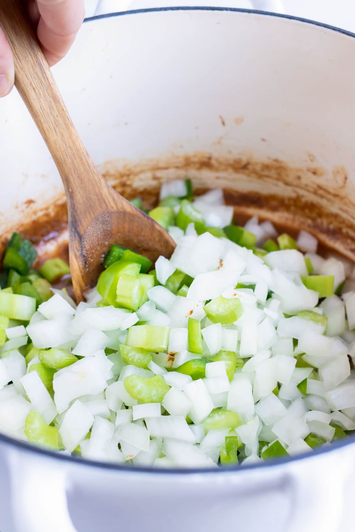 Onions, bell pepper, and celery are sautéed on the stove.