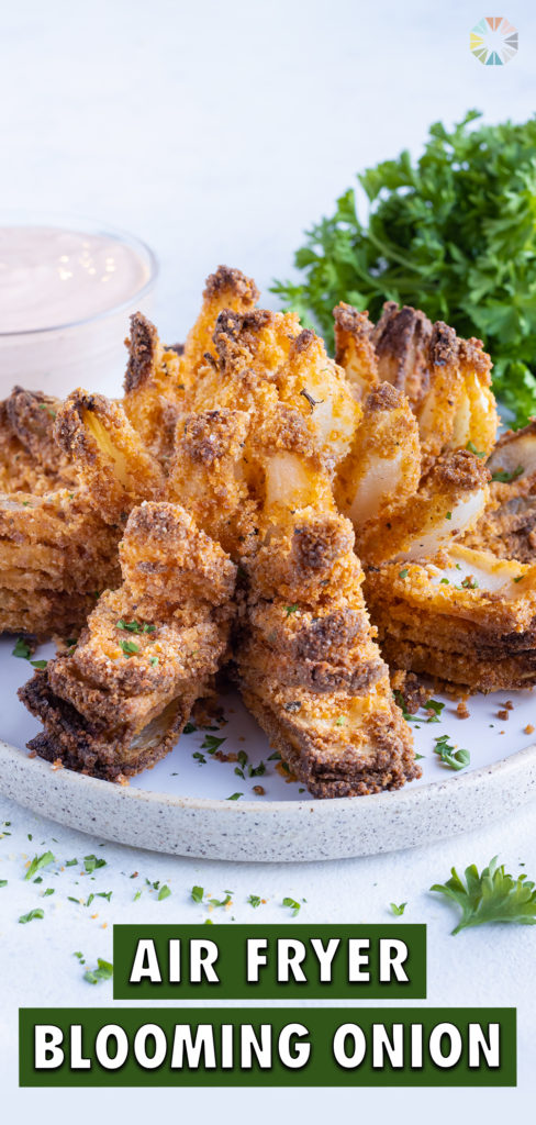 Fried blooming onion is topped with fresh parsley and plated for an appetizer.
