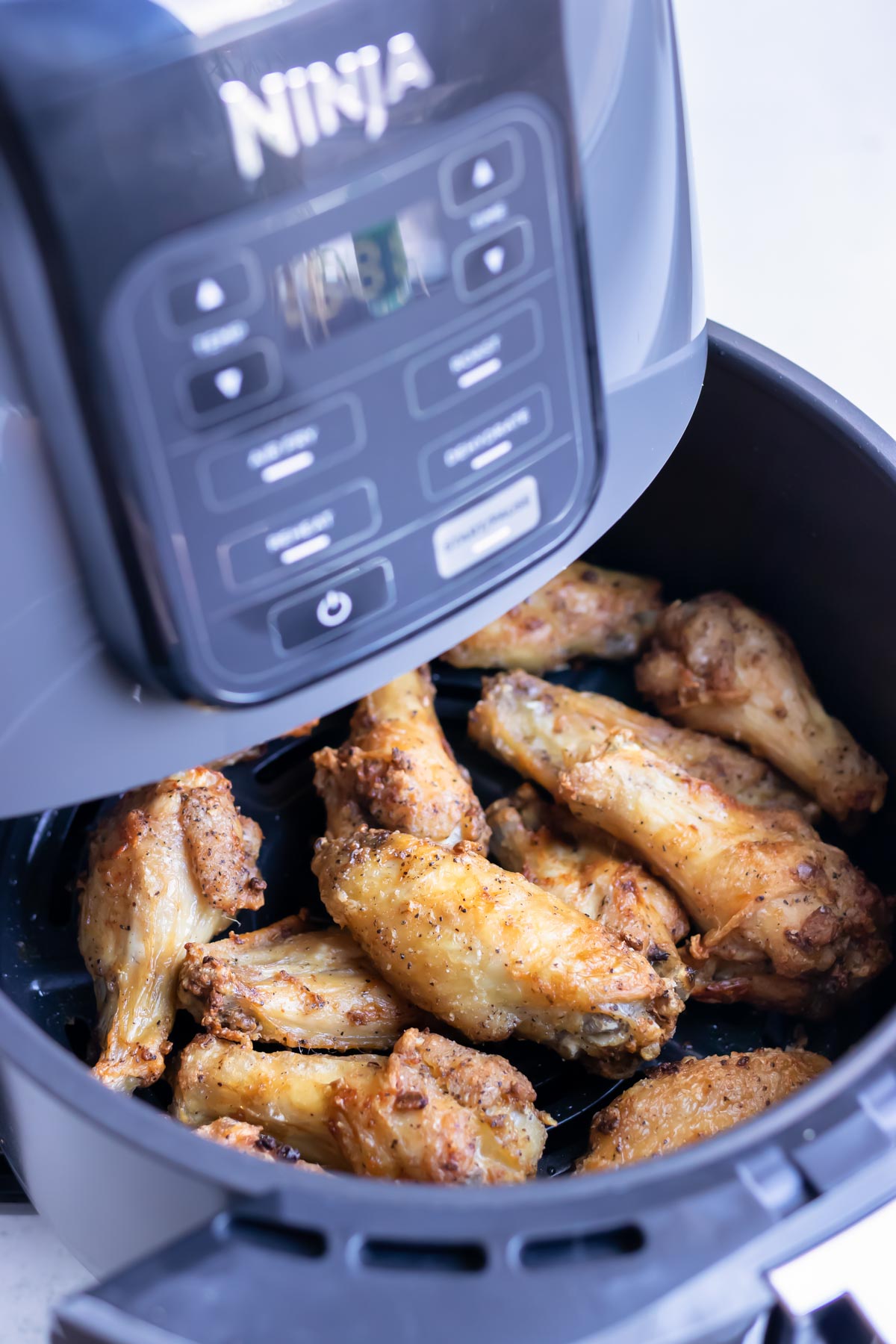 Crispy chicken wings are cooked in a Ninja air fryer.