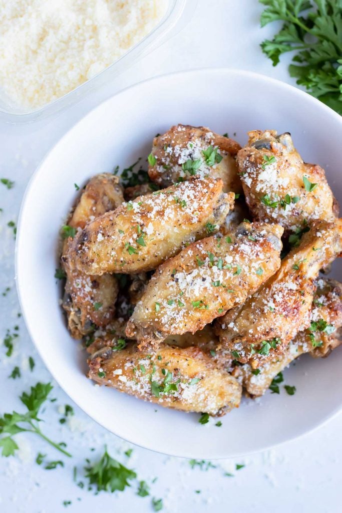 Air fryer chicken wings are served in a white bowl for healthy party food.