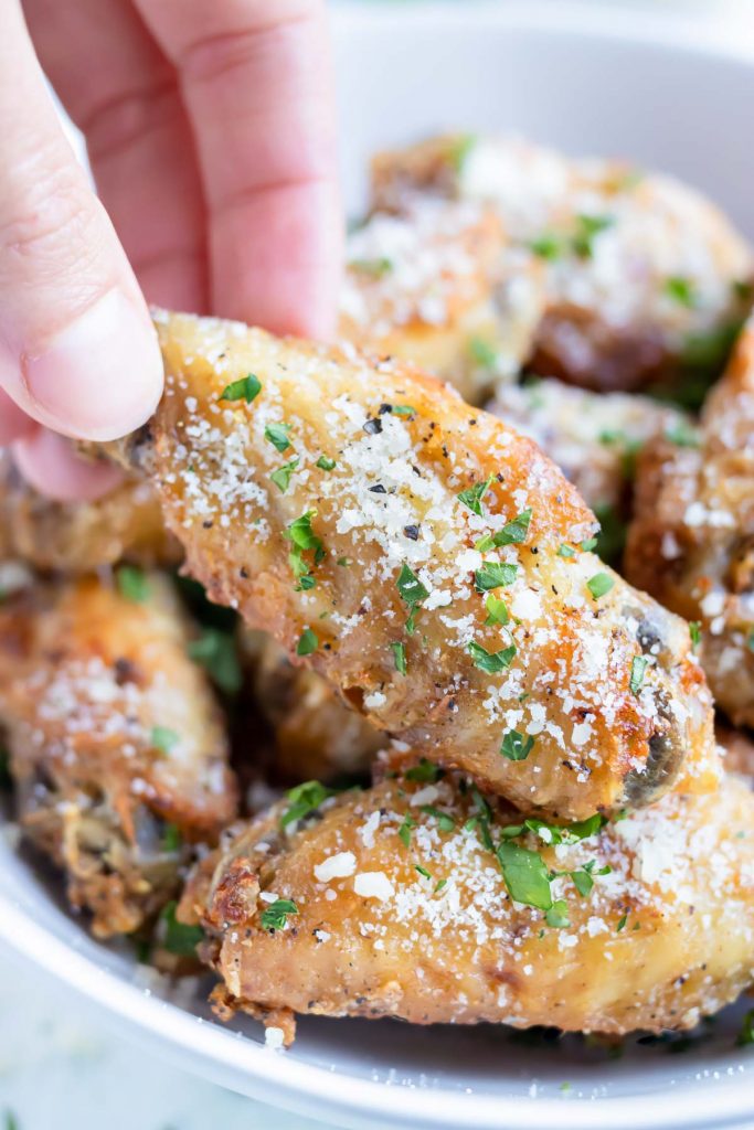 Crispy air fryer chicken wings are picked up for an appetizer.
