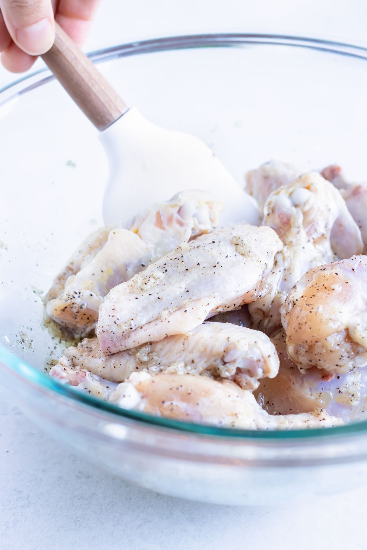Raw chicken wings are coated in the oil and seasoning mixture.