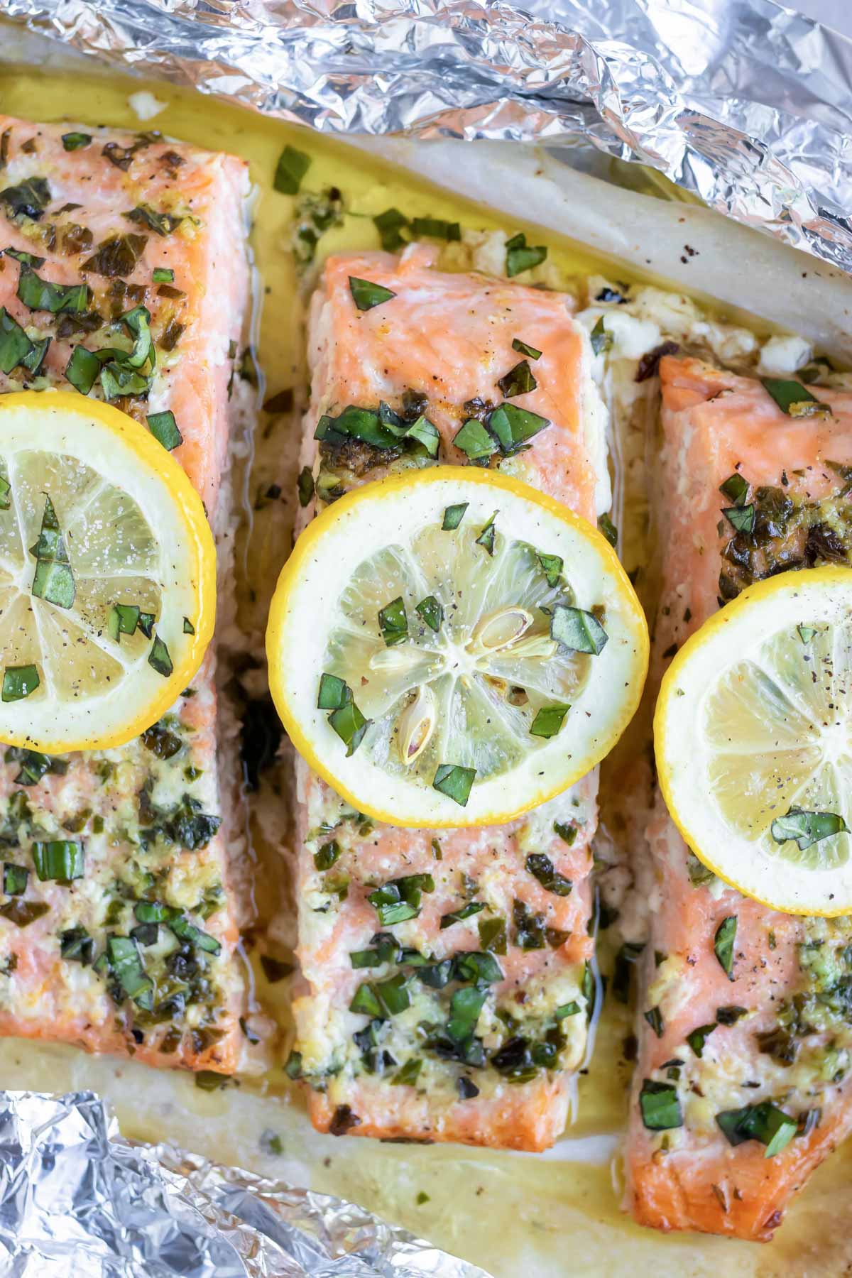 A close-up image of a lemon basil baked salmon recipe that has been baked in foil packets.