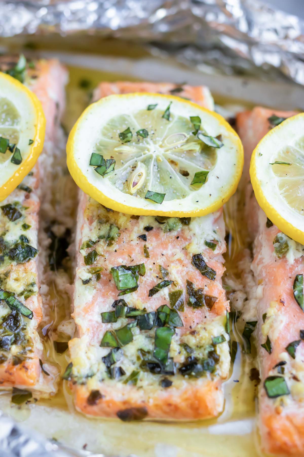 A fillet of fish with chopped fresh basil and lemon slices.
