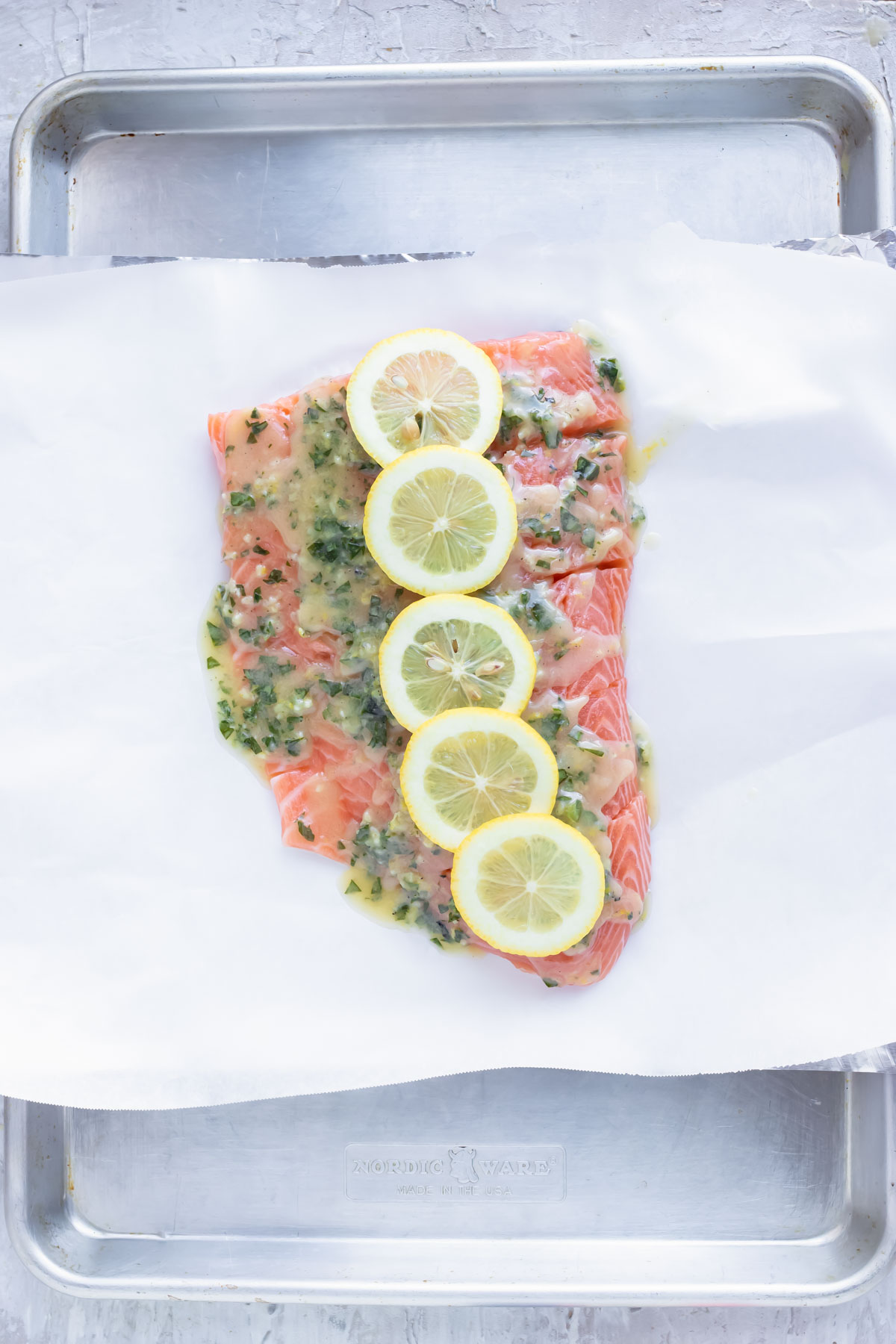 Lemon slices on top of fish on a baking sheet.