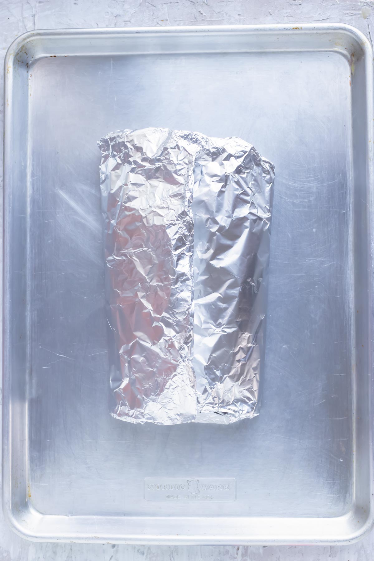Salmon in a foil packet on a baking sheet ready to be baked in the oven.