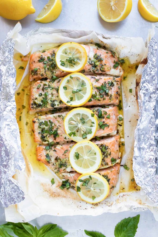 Baked basil salmon wrapped in foil and topped with lemon slices.