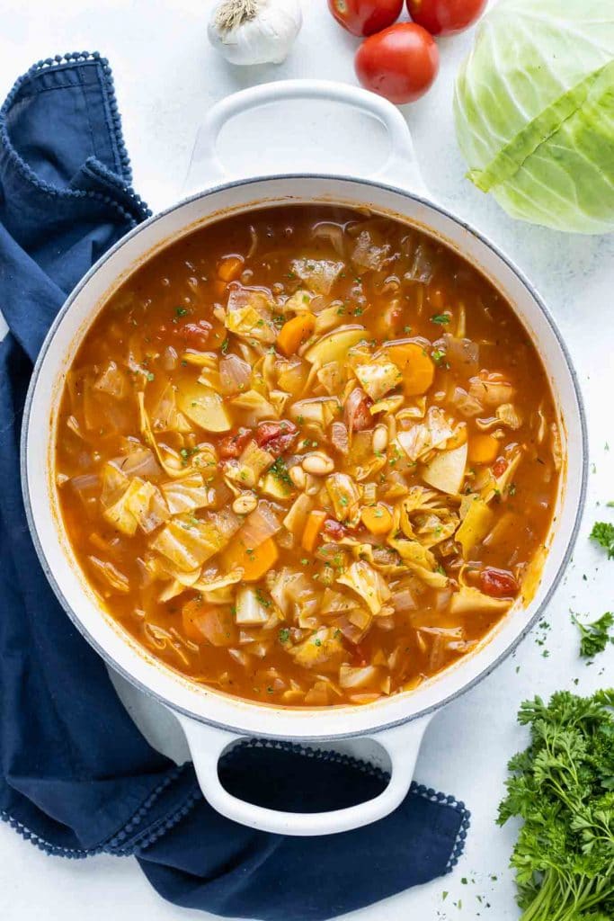 Cabbage soup is served from a big pot for a vegan meal.