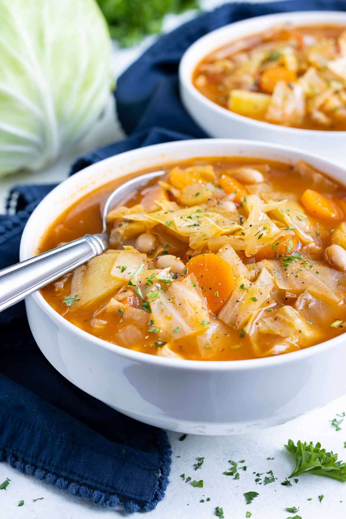 Healthy and low carb soup is served in a white bowl with a spoon.