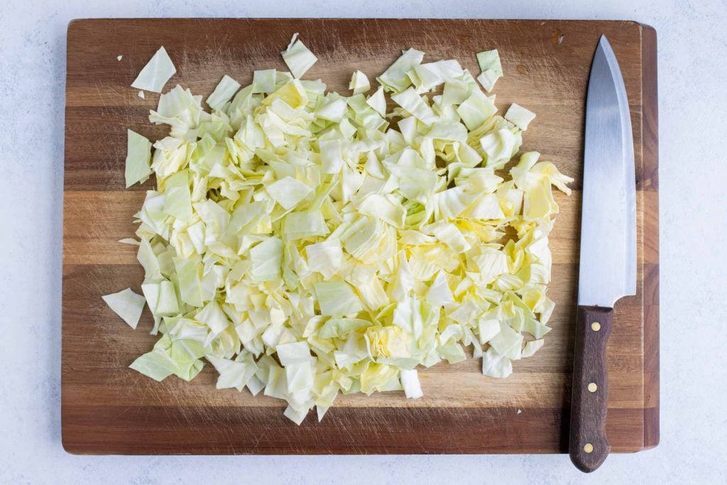 Green cabbage chopped into 1-inch pieces on a wooden board for easy cabbage soup.