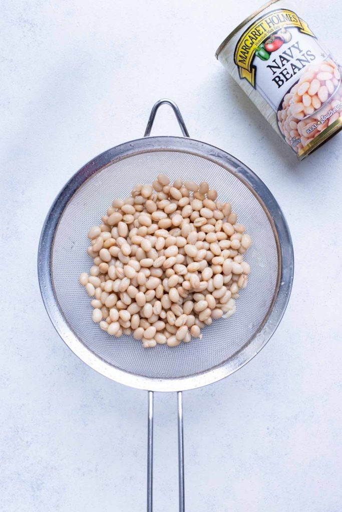 Canned white beans rinsing in a strainer for cabbage and white bean soup.