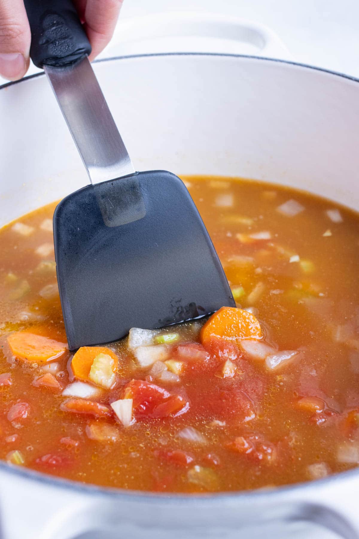 Broth and canned vegetables are added to the pot.