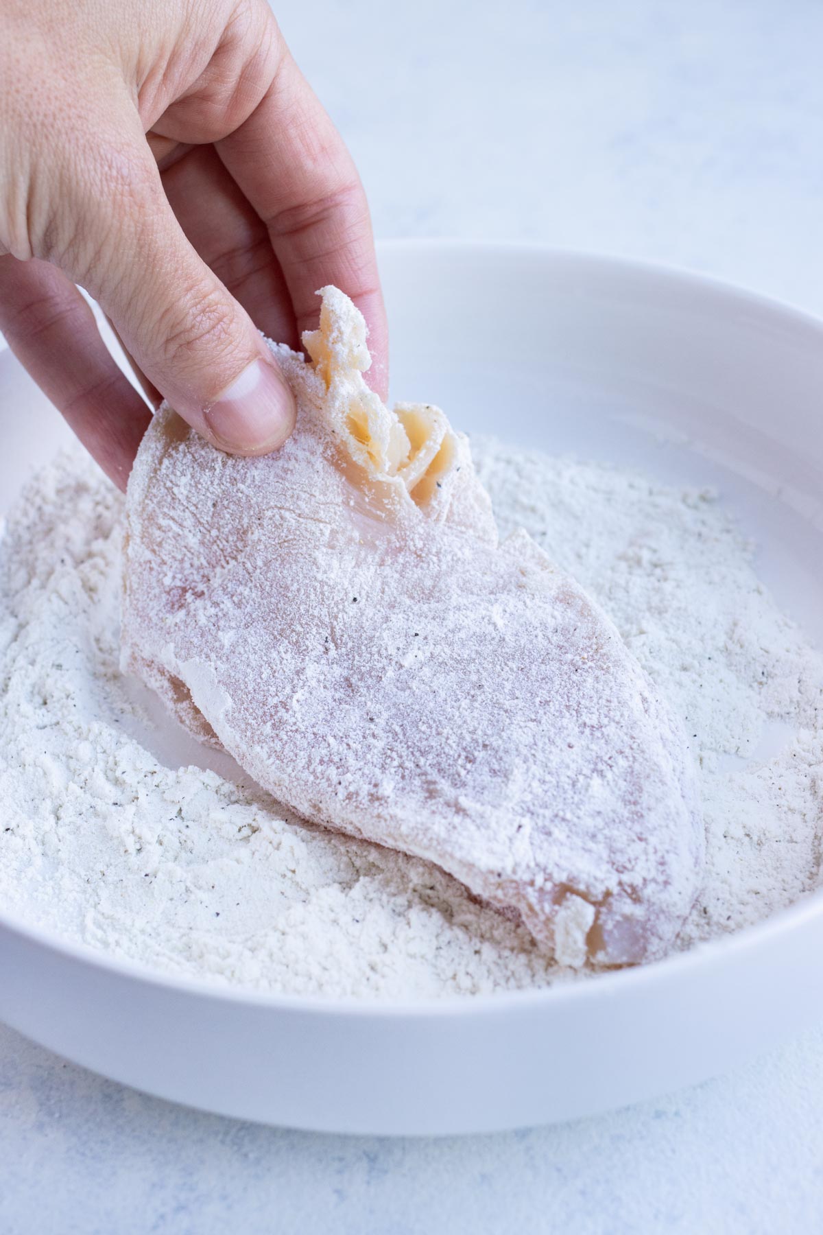 Chicken is covered in flour before cooking.