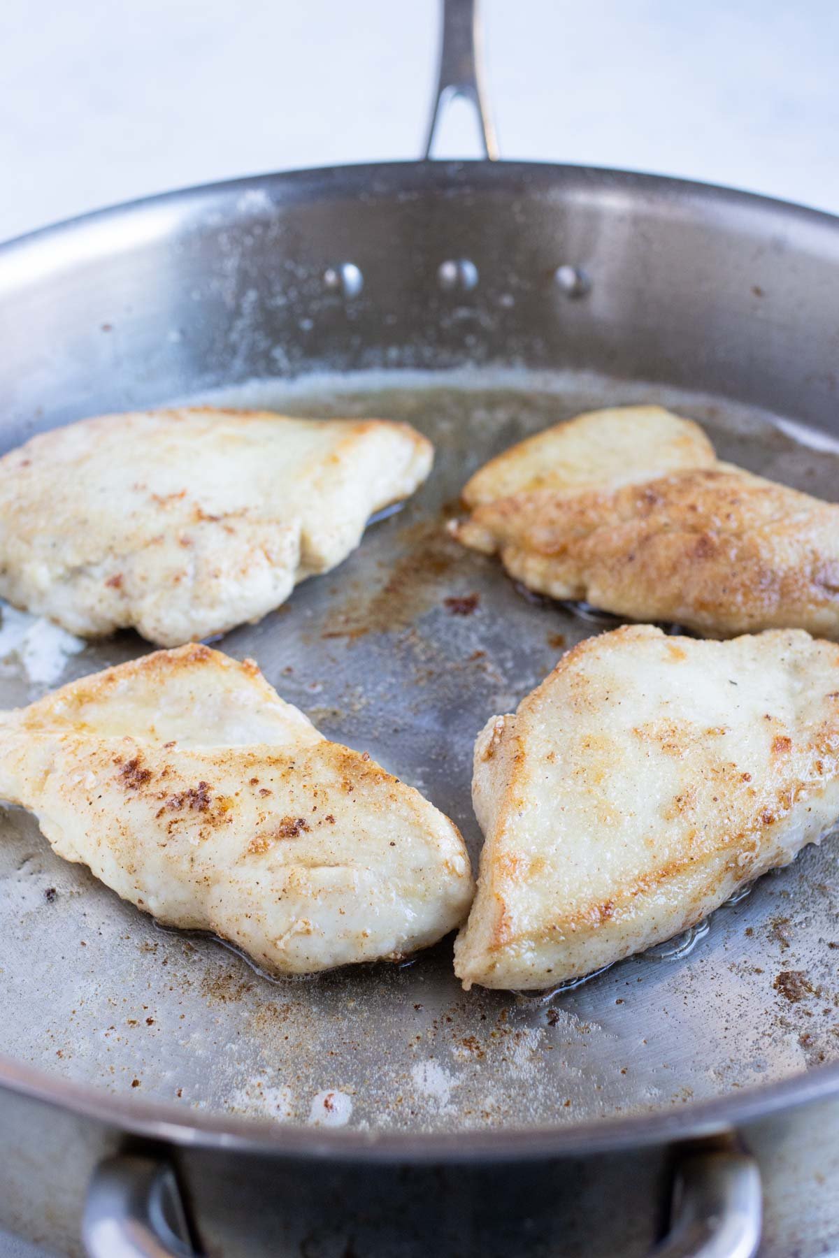 Coated chicken is cooked on the stove until crispy.