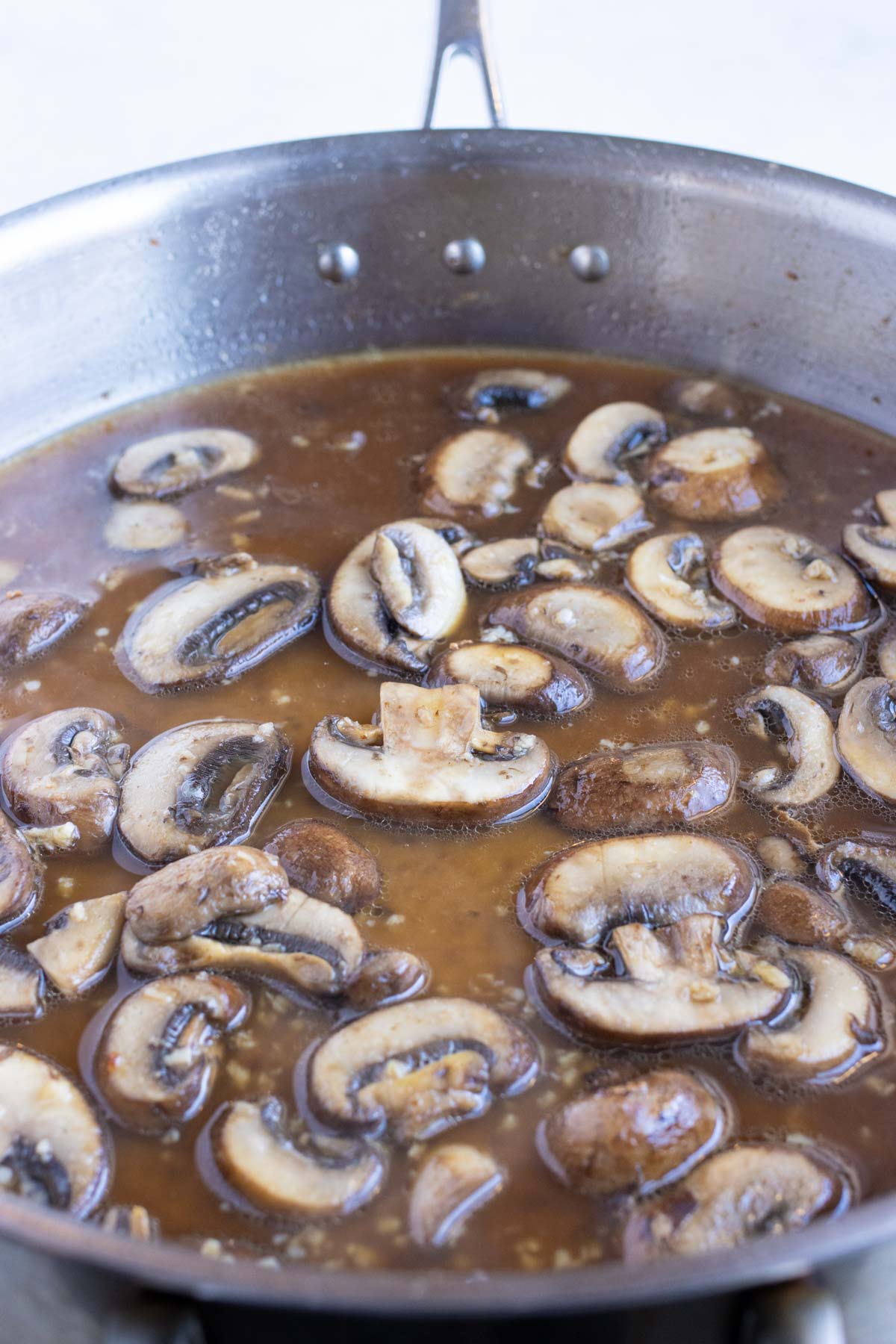 Mushrooms and liquids are cooked on the stove.