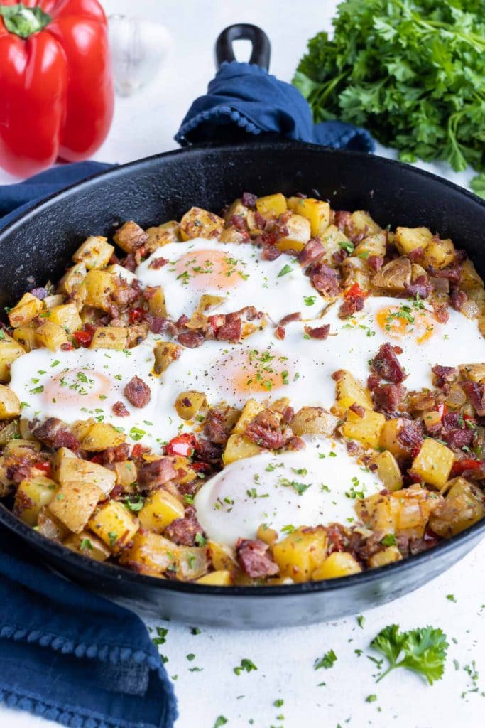 Healthy corned beef hash and eggs are made in a cast-iron skillet for breakfast.