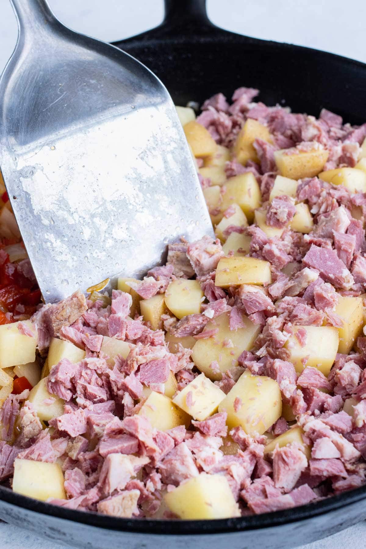 Corned beef and potatoes are added to the skillet.