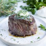 Garlic herb butter is melted on top of a steak.
