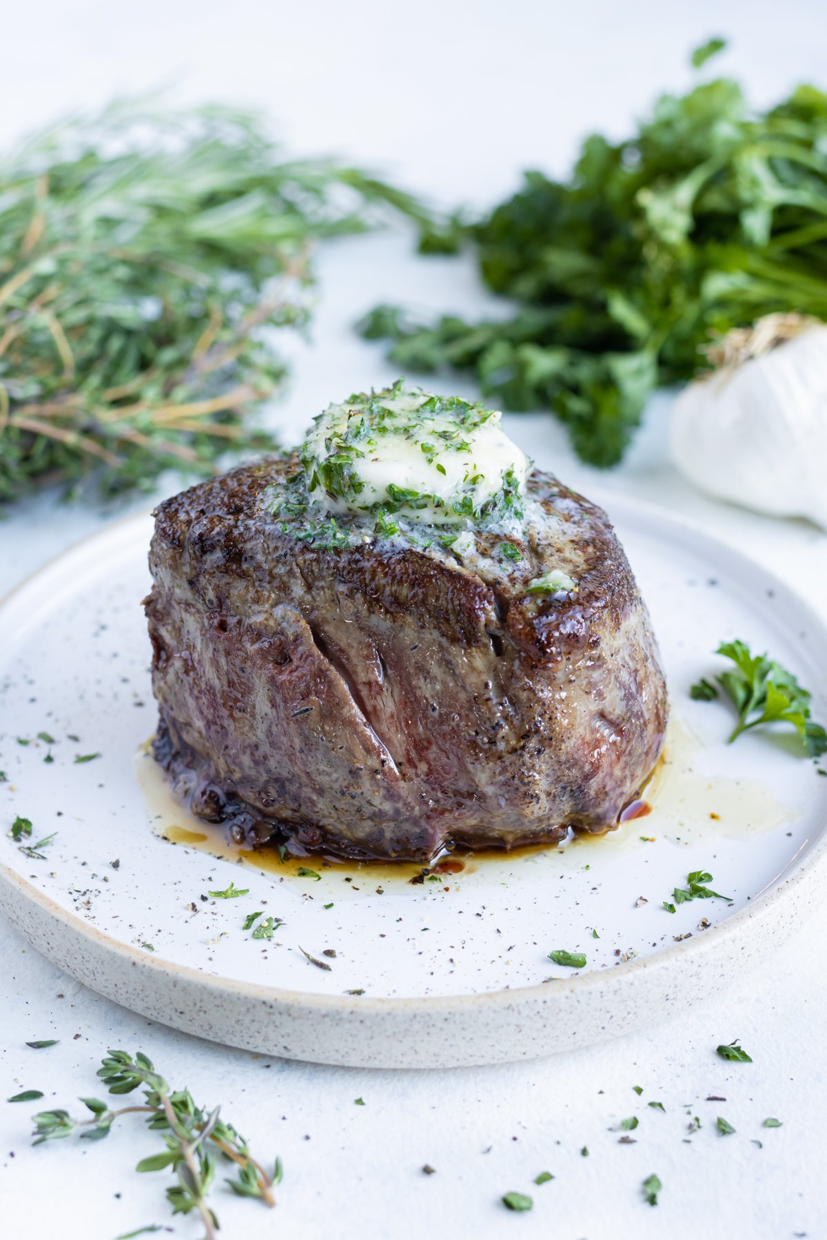 Garlic herb butter is melted on top of a steak.