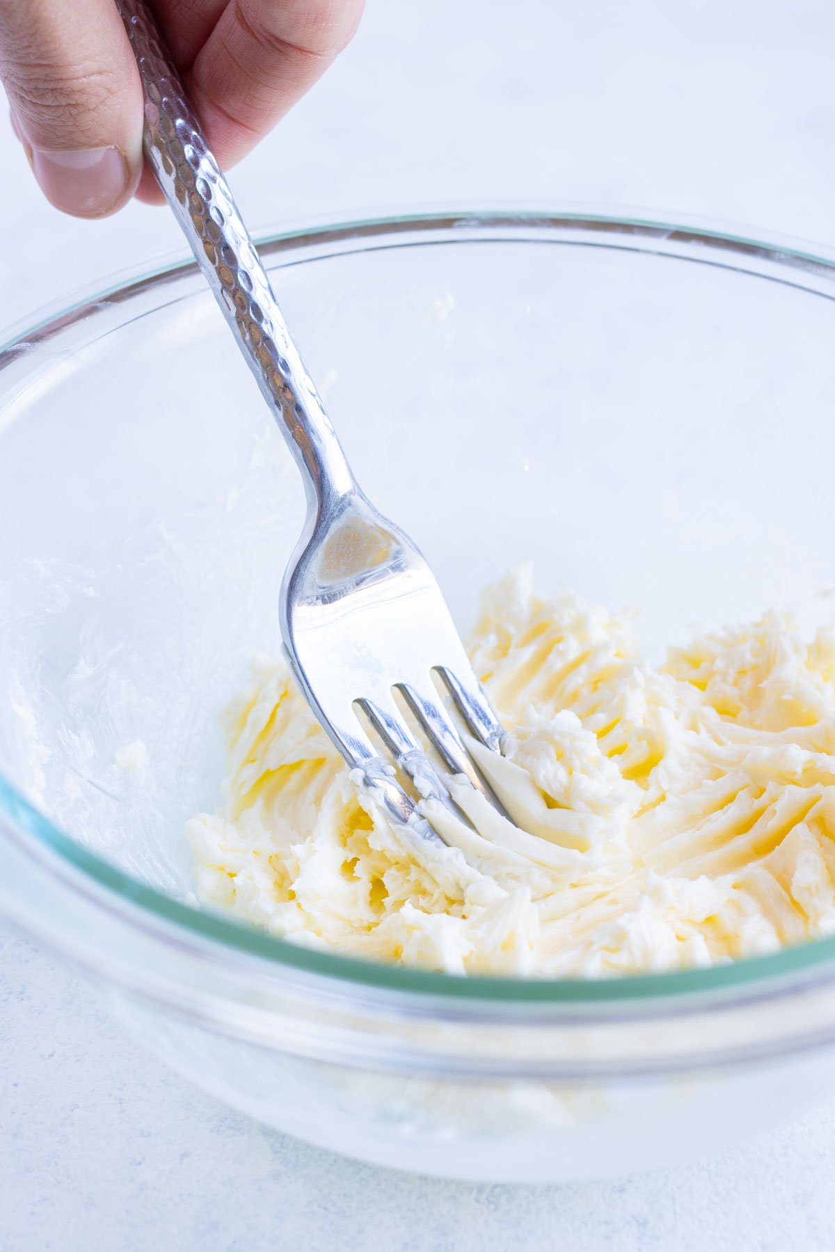 Butter is mashed with a fork in a bowl