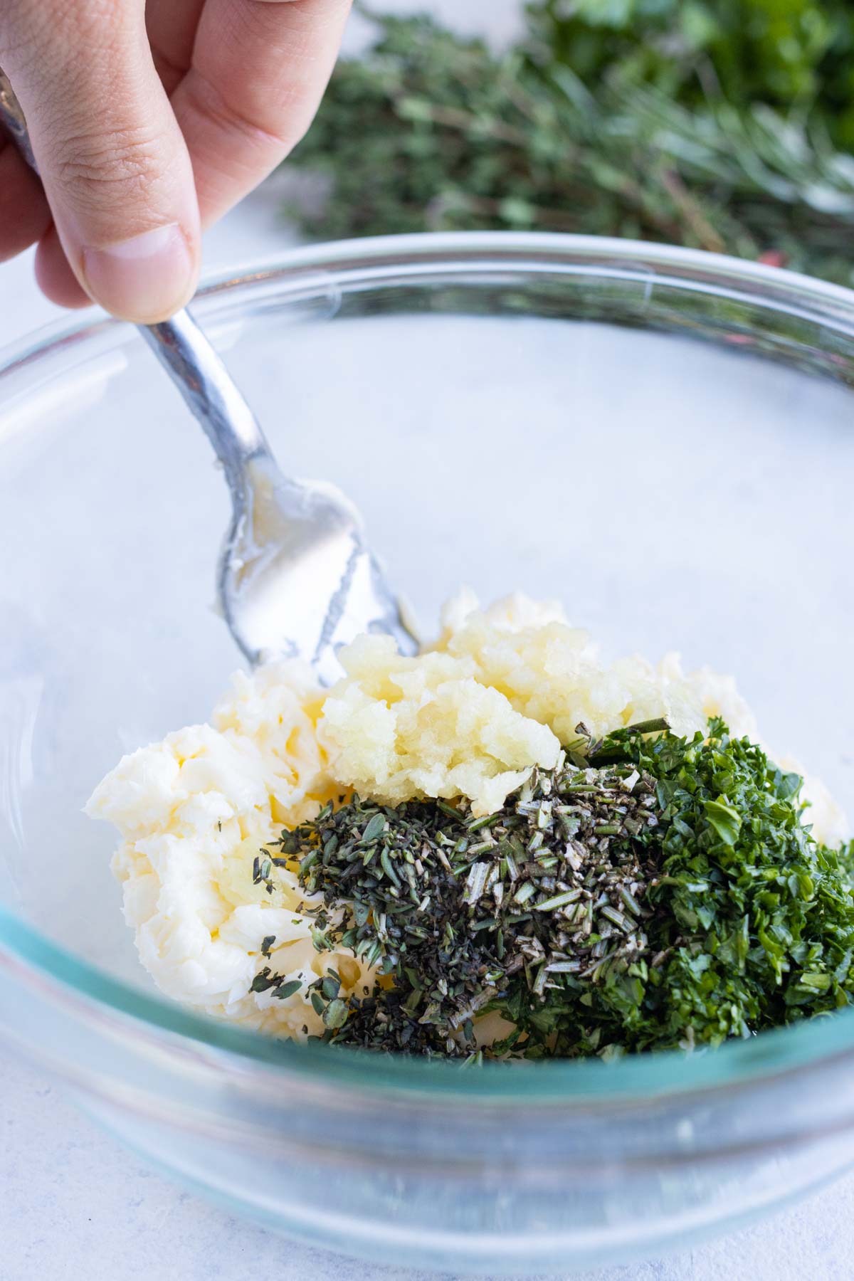 Herbs, garlic, salt, and pepper are added to the butter.