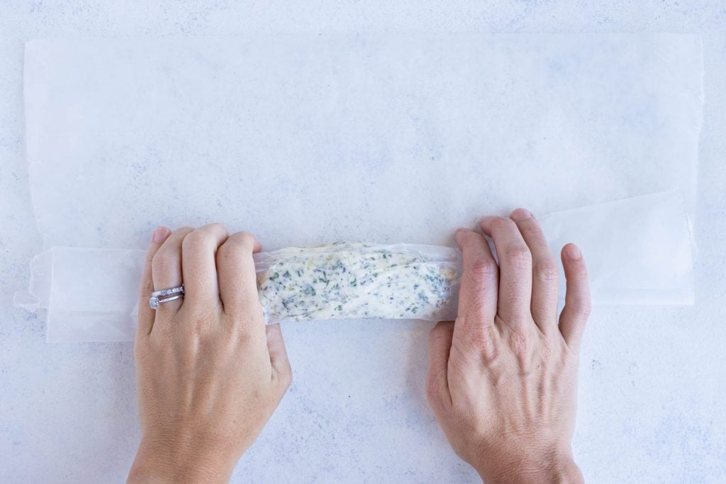 Butter is rolled into a log using the parchment paper.