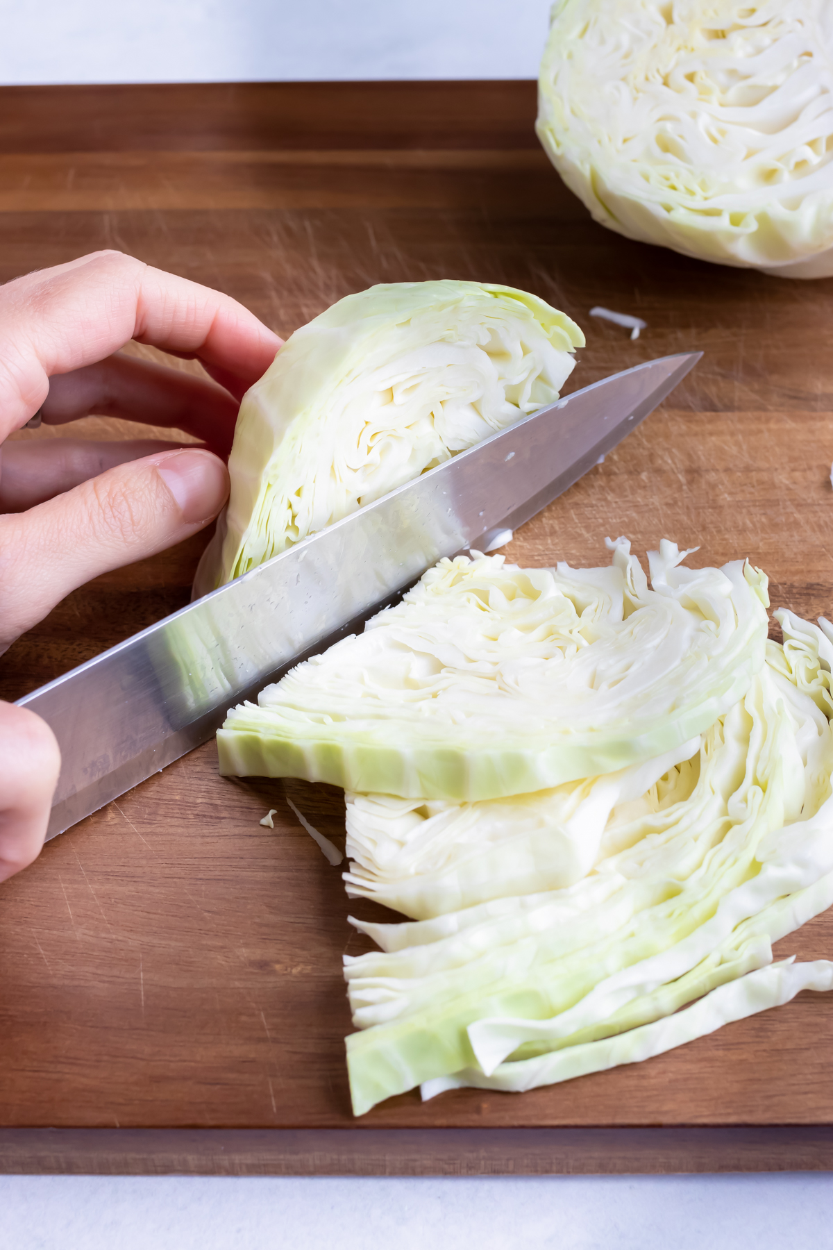 Shredding cabbage by thinly slicing it with a knife.