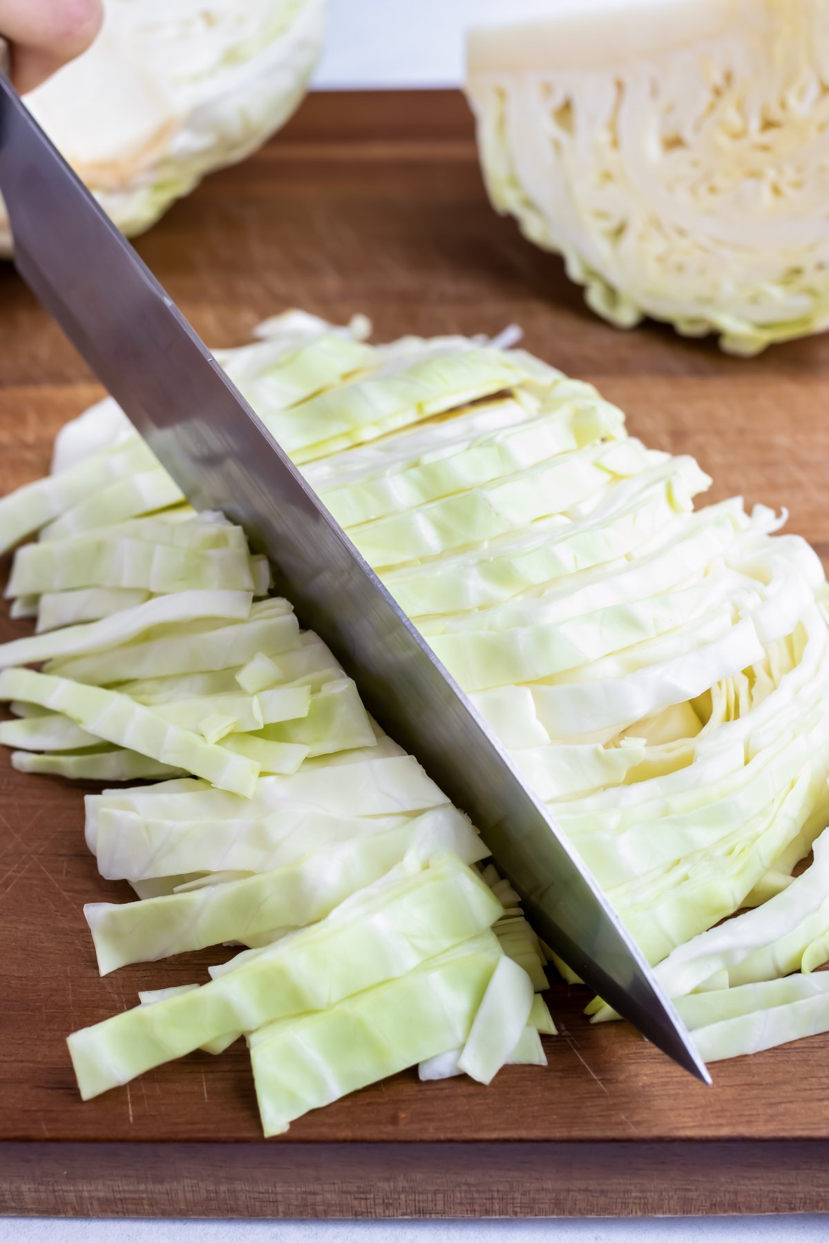 A knife cutting cabbage into thin 1-inch pieces.