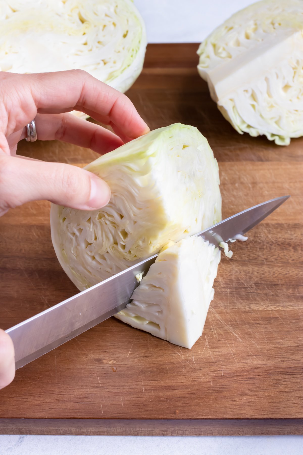 Removing the core of the cabbage by cutting at an angle with a knife.