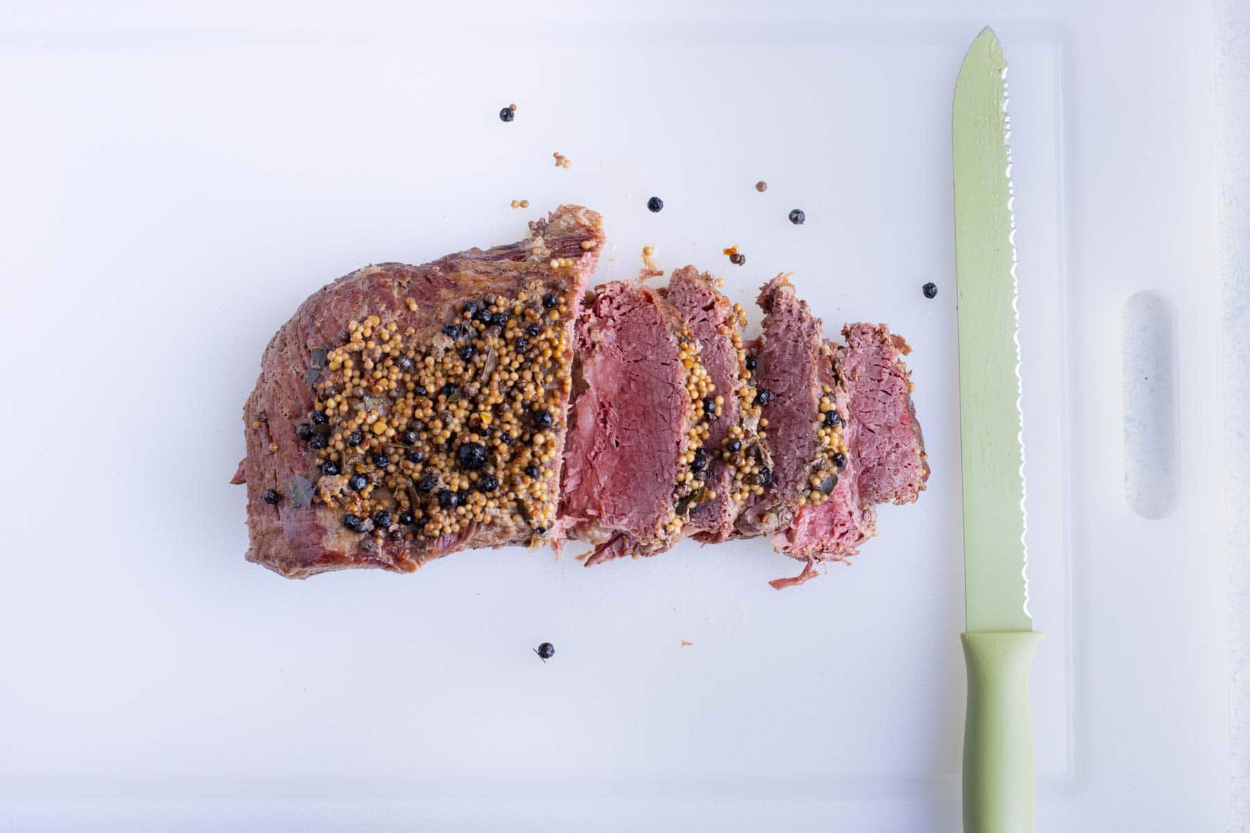 Corned beef is sliced with a knife.