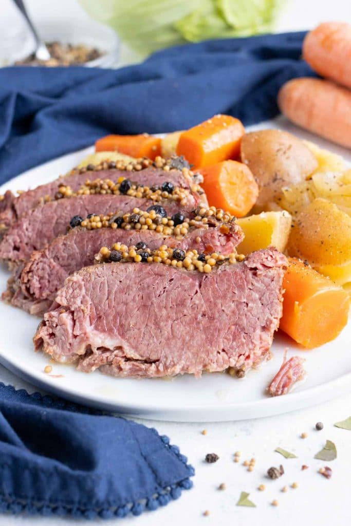 Sliced corned beef brisket is served with tender carrots, potatoes, and cabbage.