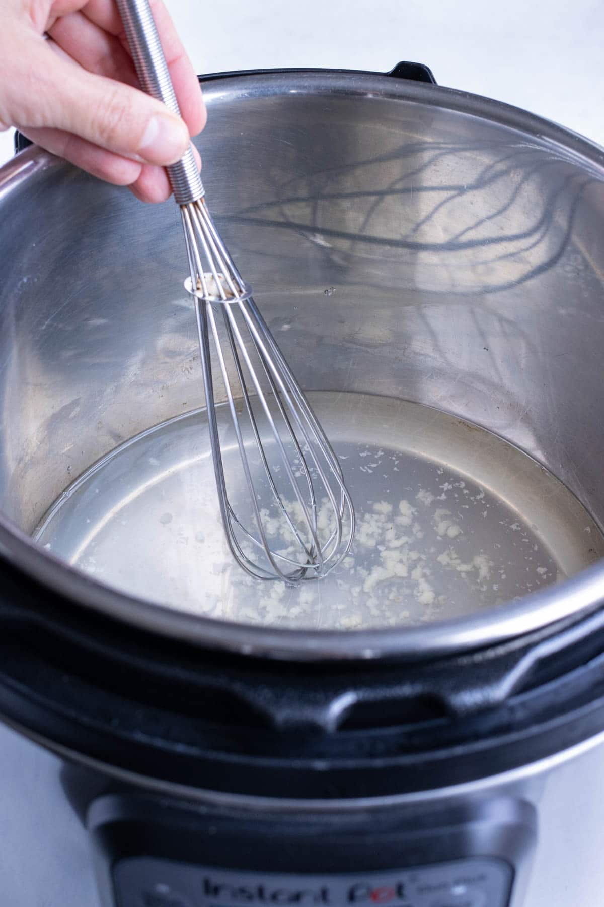 Water, vinegar, and sugar are whisked together in the pressure cooker.