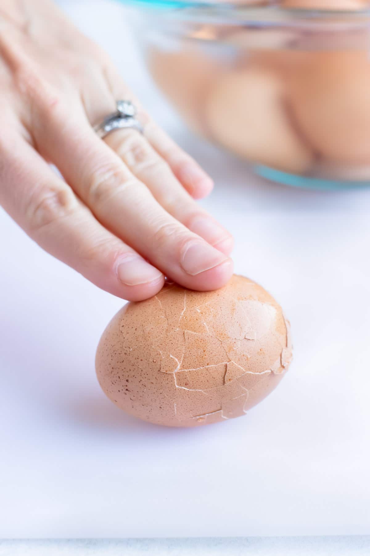 A hand rolling a cracked hard boiled egg to make Instant Pot hard boiled eggs.