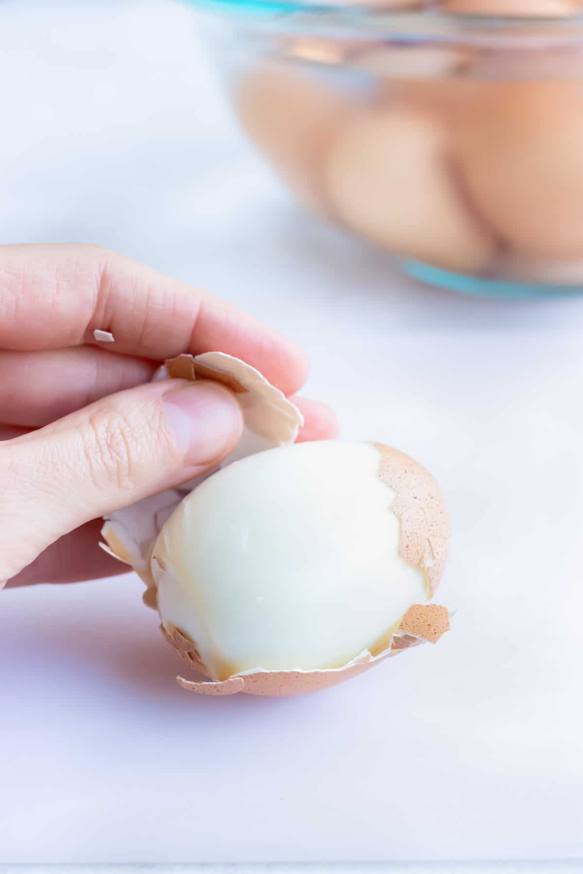 A hand pulling the shell off a hard boiled egg to make Instant Pot hard boiled eggs.