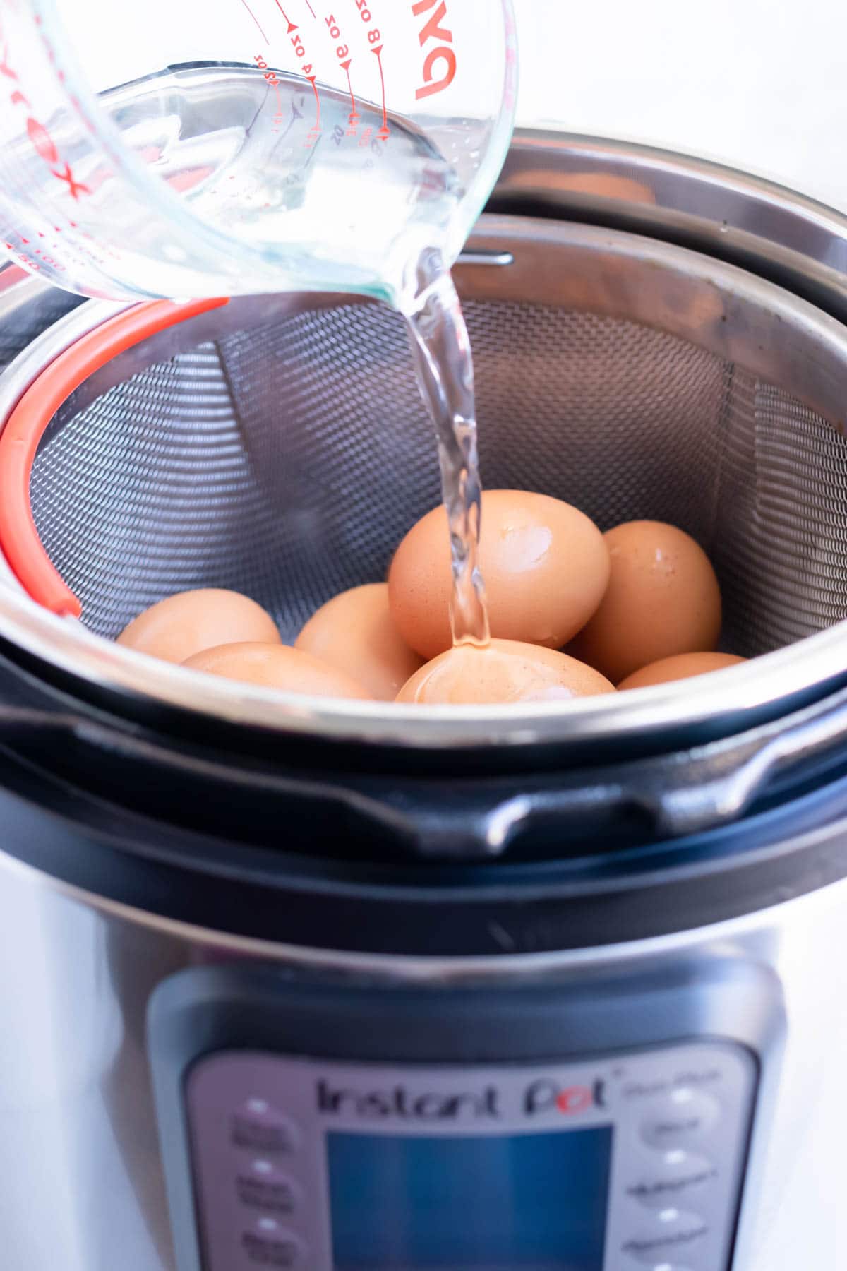 Cold water being poured over eggs into an instant pot.