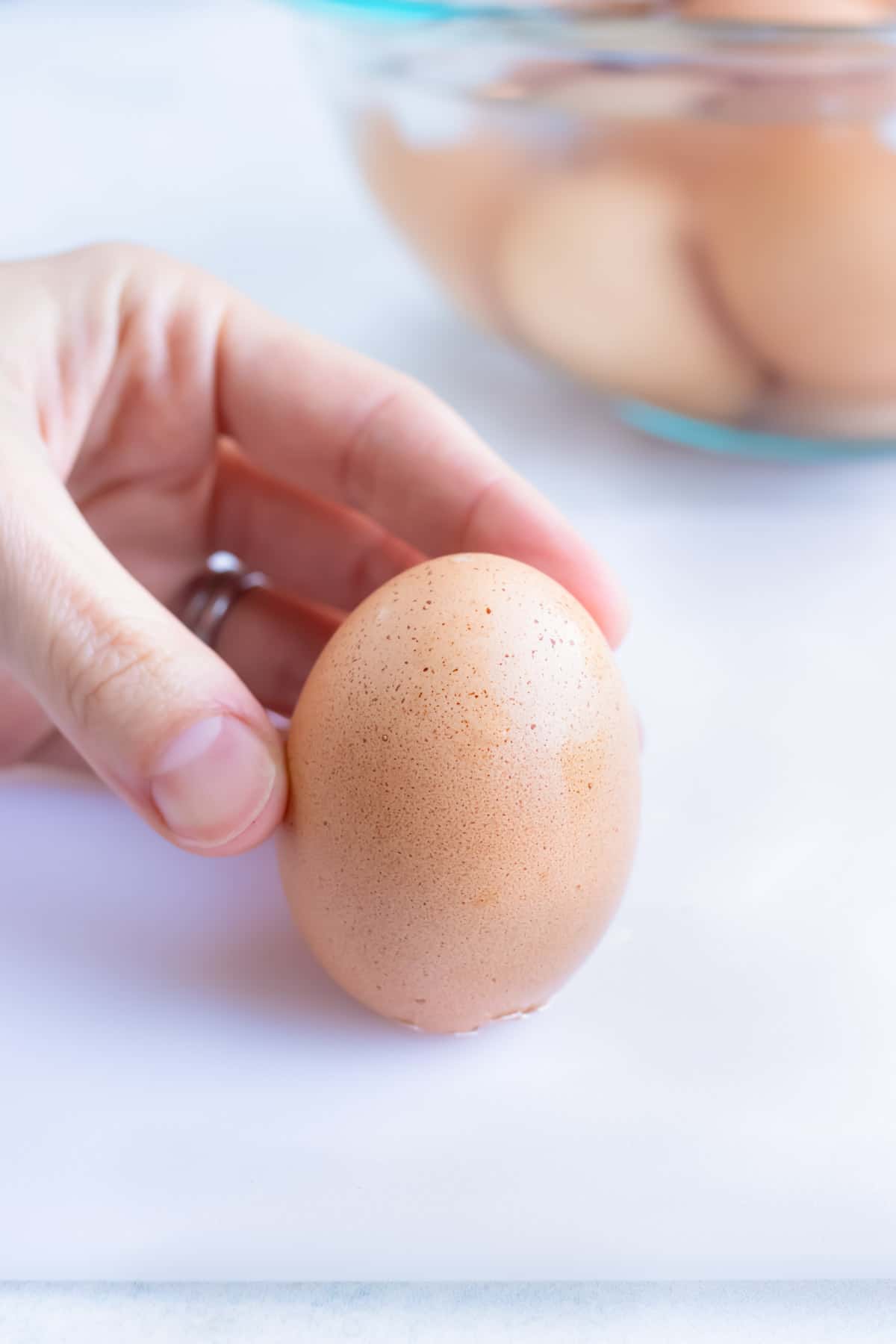 A hand cracking the flat end of a hard boiled egg to make Instant Pot hard boiled eggs.