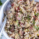 A bowl of traditional Instant Pot Jambalaya is served in a white bowl with a spoon.