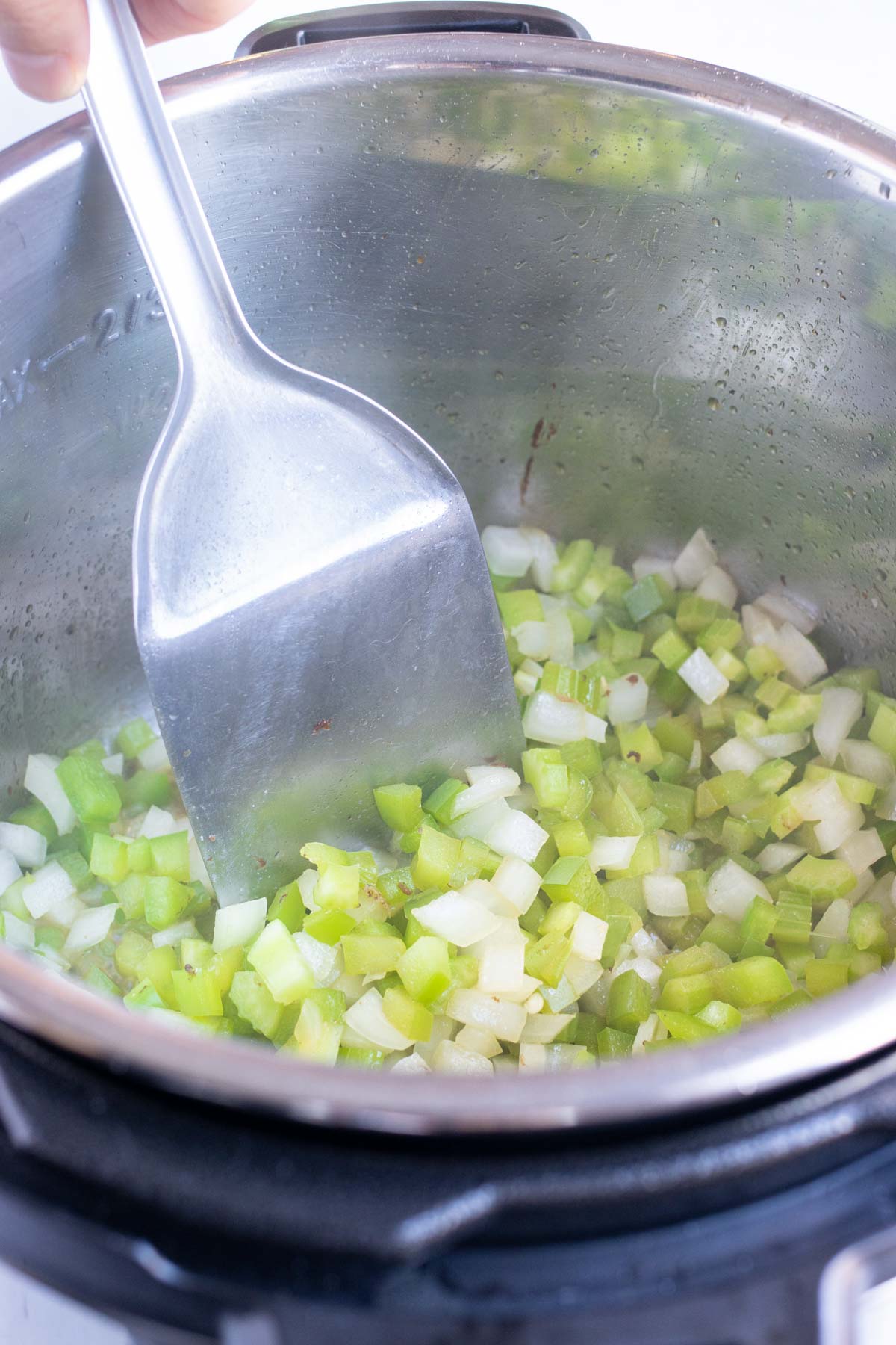 Diced onions, peppers, and celery are sautéd in the pressure cooker.