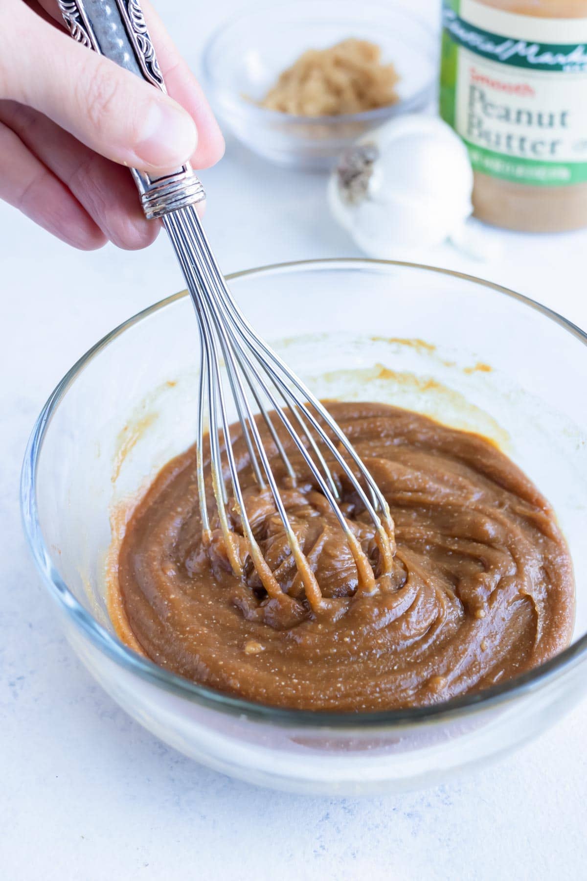 Ingredients for this peanut dipping sauce are mixed together in a glass bowl.